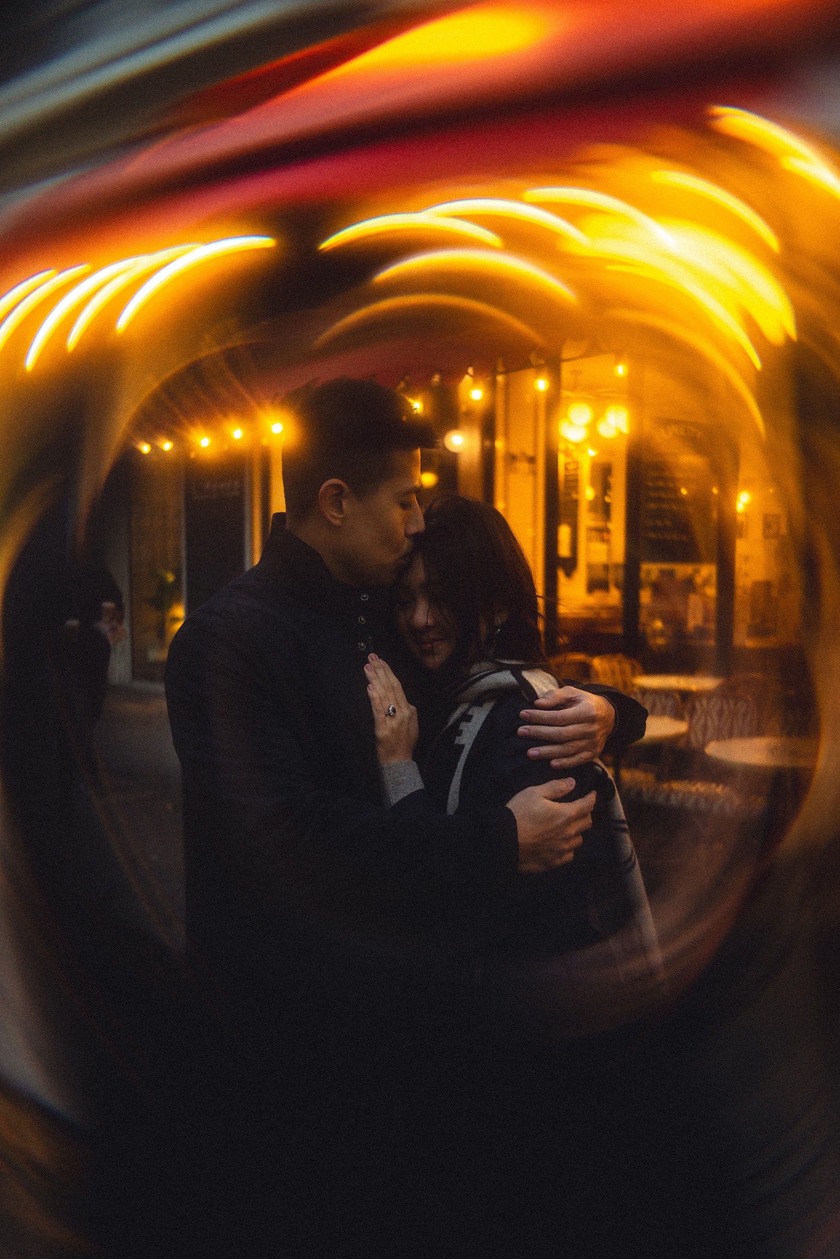 Patrick and Ivy embraced under cafe lights in Paris, framed through a lensball